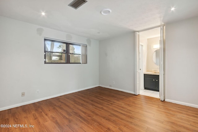 unfurnished bedroom featuring light wood-type flooring and ensuite bathroom