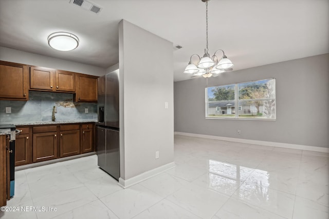 kitchen with sink, an inviting chandelier, stove, decorative light fixtures, and decorative backsplash