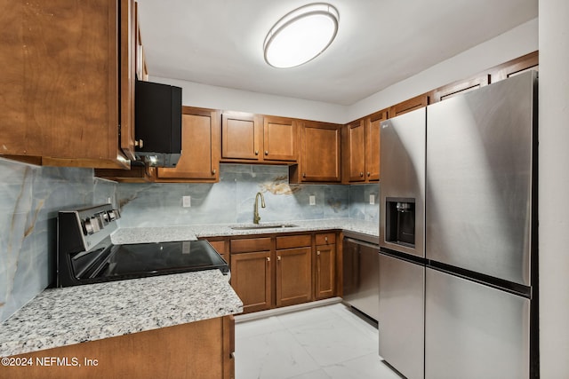 kitchen featuring backsplash, light stone countertops, sink, and appliances with stainless steel finishes