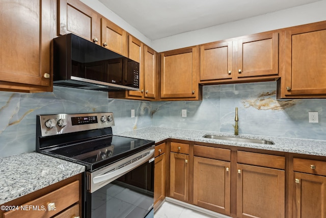 kitchen with light stone countertops, electric range, tasteful backsplash, and sink