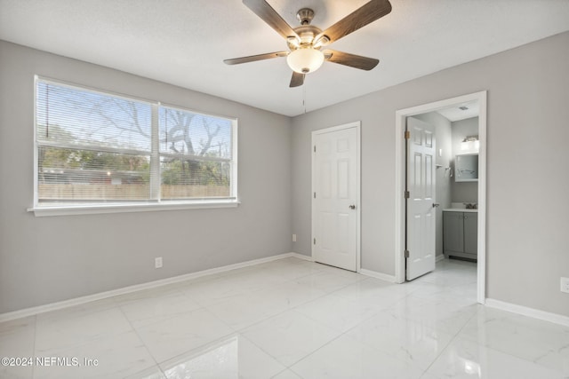 unfurnished bedroom with multiple windows, ceiling fan, and ensuite bath