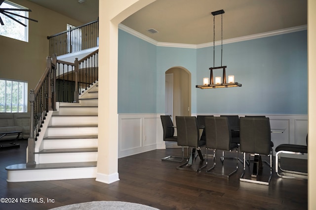 dining area with dark hardwood / wood-style flooring, ornamental molding, and an inviting chandelier