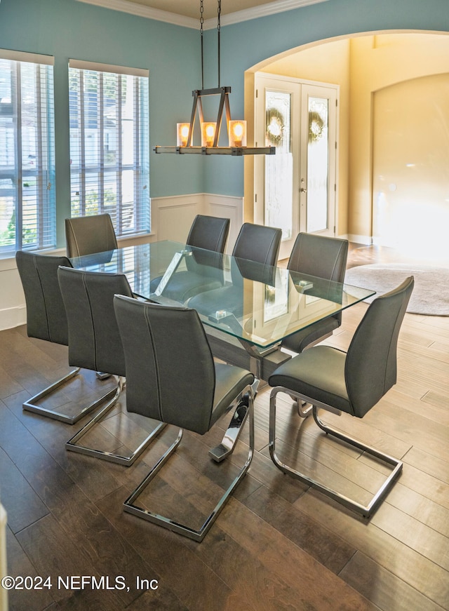 dining space with hardwood / wood-style floors, ornamental molding, a wealth of natural light, and french doors