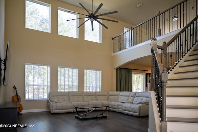 living room with ceiling fan, dark hardwood / wood-style flooring, and a towering ceiling