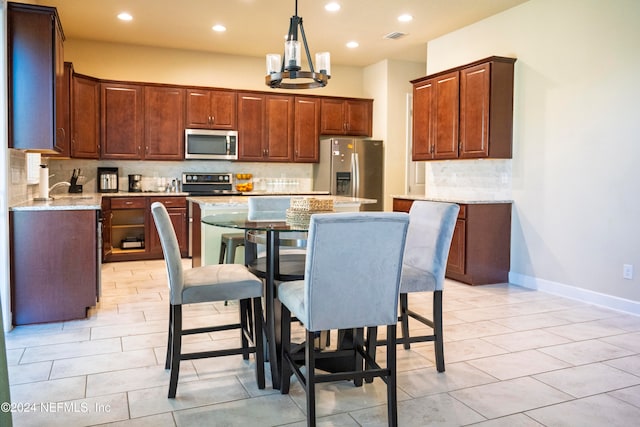 kitchen with light stone counters, pendant lighting, a kitchen island, and stainless steel appliances