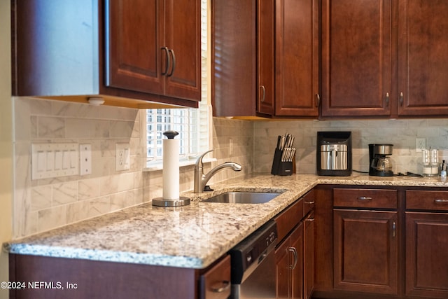 kitchen featuring tasteful backsplash, light stone countertops, sink, and stainless steel dishwasher