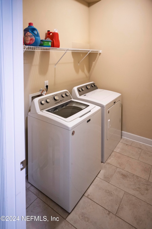 clothes washing area with washer and dryer and light tile patterned floors