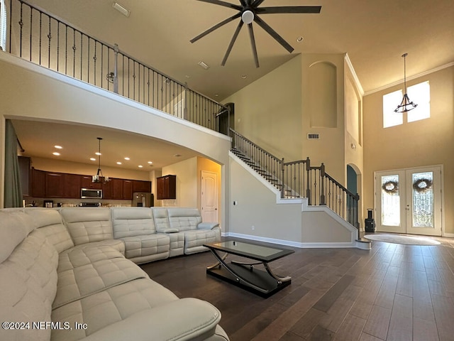 living room featuring ceiling fan with notable chandelier, dark hardwood / wood-style flooring, a towering ceiling, and french doors