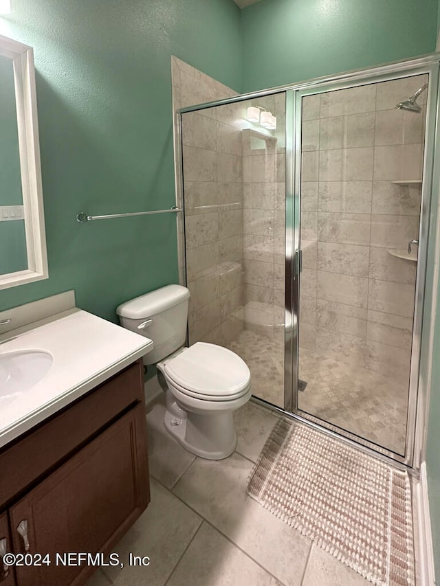 bathroom featuring tile patterned floors, vanity, toilet, and walk in shower