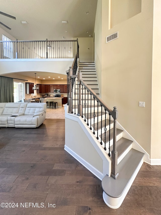 stairway featuring hardwood / wood-style floors and a towering ceiling