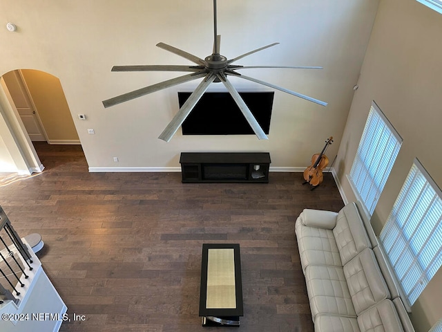 unfurnished living room with ceiling fan, dark hardwood / wood-style flooring, and a towering ceiling