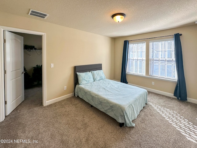 carpeted bedroom with a spacious closet, a closet, and a textured ceiling