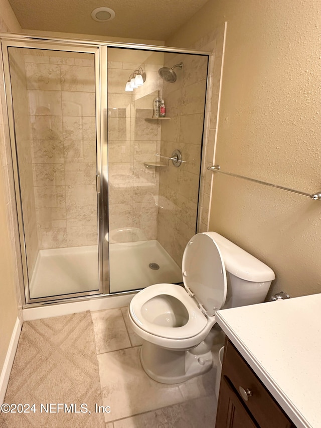 bathroom with tile patterned floors, toilet, and a shower with door