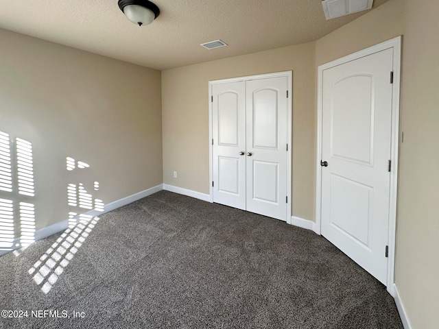 unfurnished bedroom with carpet flooring, a textured ceiling, and a closet