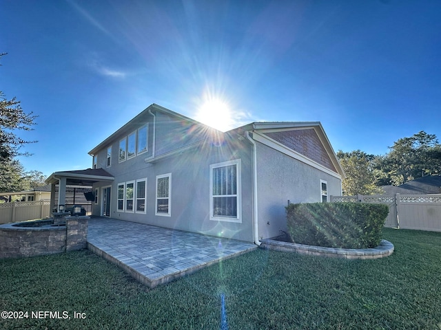 rear view of house featuring a lawn and a patio