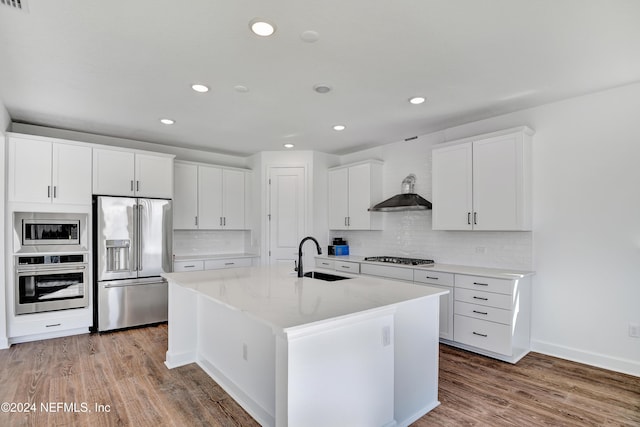 kitchen featuring light stone counters, stainless steel appliances, a kitchen island with sink, sink, and white cabinetry