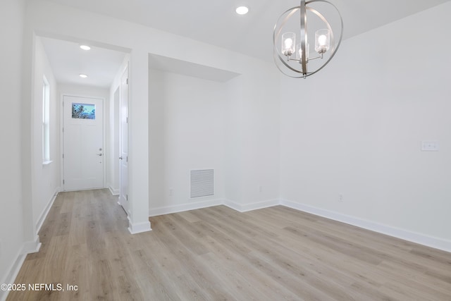 unfurnished dining area with an inviting chandelier and light hardwood / wood-style flooring