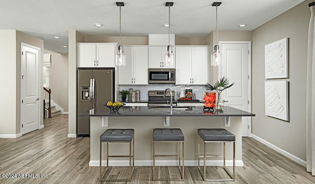 kitchen featuring sink, stainless steel appliances, light hardwood / wood-style flooring, a kitchen island with sink, and white cabinets