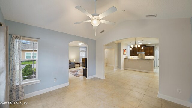 unfurnished living room featuring a healthy amount of sunlight, ceiling fan, lofted ceiling, and light tile patterned flooring