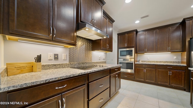 kitchen with light stone countertops, appliances with stainless steel finishes, tasteful backsplash, dark brown cabinets, and light tile patterned floors