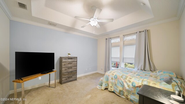 carpeted bedroom with a tray ceiling, ceiling fan, and ornamental molding