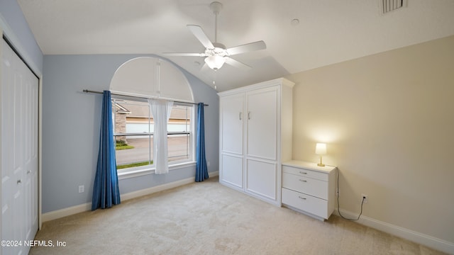 unfurnished bedroom featuring light carpet, a closet, ceiling fan, and lofted ceiling