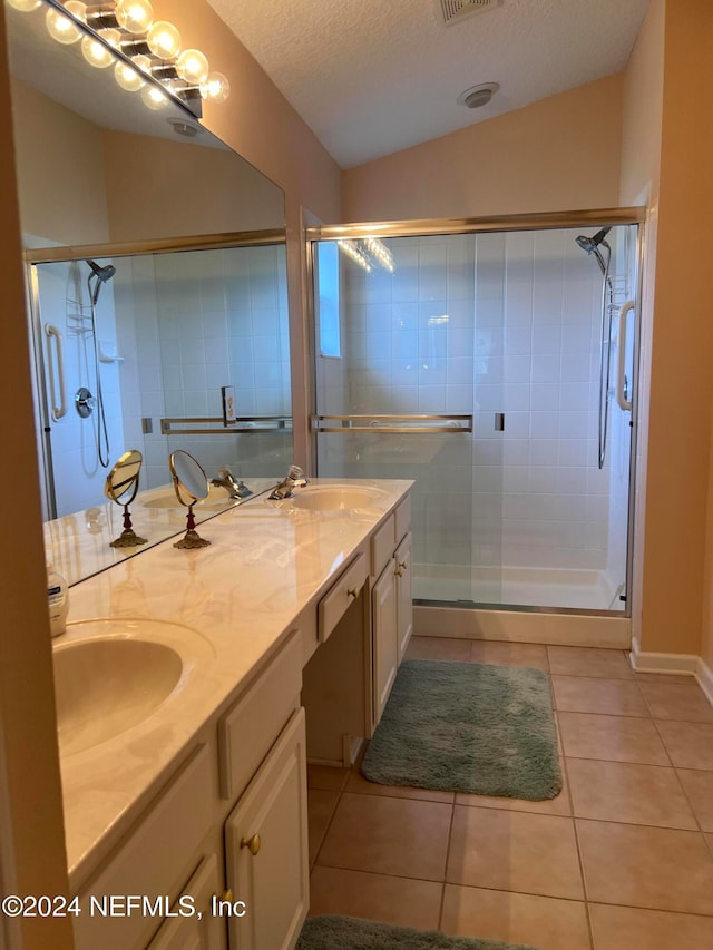 bathroom featuring vanity, a shower with door, lofted ceiling, tile patterned flooring, and a textured ceiling