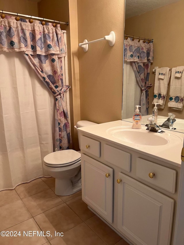 bathroom with tile patterned flooring, a textured ceiling, vanity, and toilet