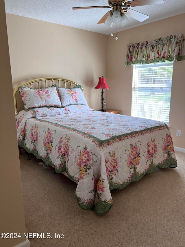 carpeted bedroom with ceiling fan and a textured ceiling