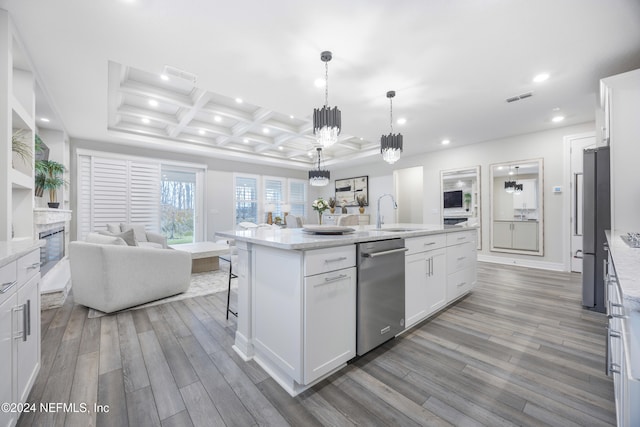 kitchen with coffered ceiling, a center island with sink, decorative light fixtures, white cabinetry, and wood-type flooring