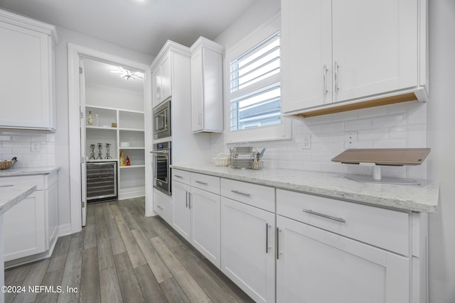 kitchen featuring dark hardwood / wood-style flooring, light stone counters, stainless steel appliances, white cabinetry, and wine cooler