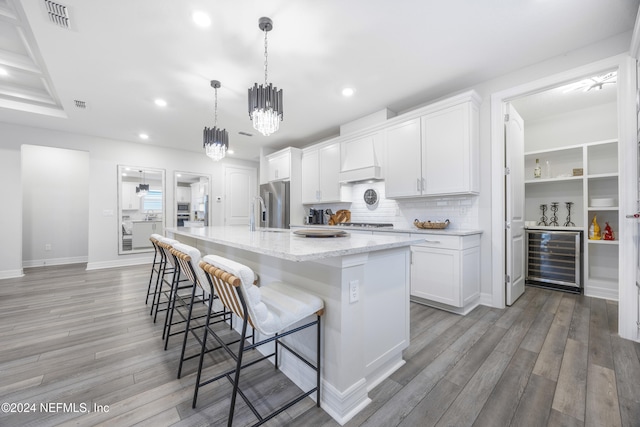 94 Hickory Pine Dr, Saint Augustine, FL 32092 - kitchen with beverage cooler, light wood-type flooring, recessed lighting, white cabinetry, and a large island with sink