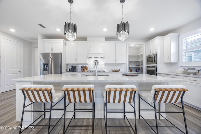 kitchen with appliances with stainless steel finishes, a center island with sink, white cabinetry, and dark wood-type flooring