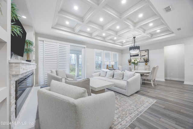 living room featuring beam ceiling, a stone fireplace, coffered ceiling, and hardwood / wood-style flooring