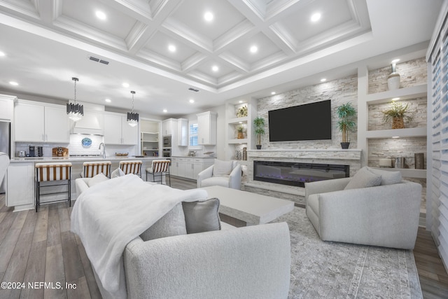 living room featuring coffered ceiling, sink, light hardwood / wood-style flooring, built in shelves, and beamed ceiling