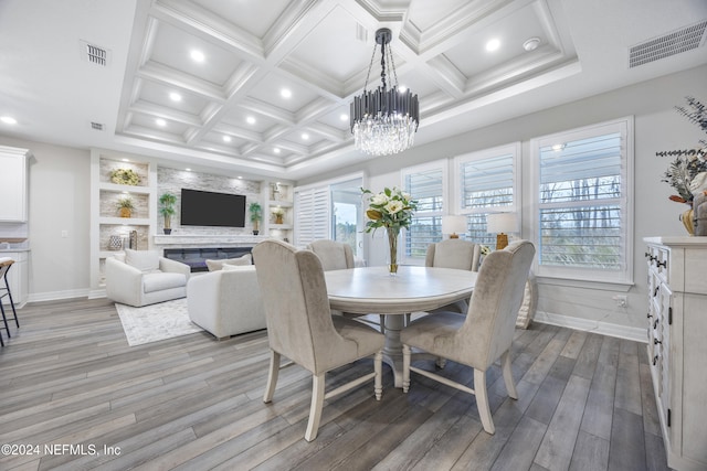 dining area featuring coffered ceiling, beam ceiling, built in features, a chandelier, and light hardwood / wood-style floors