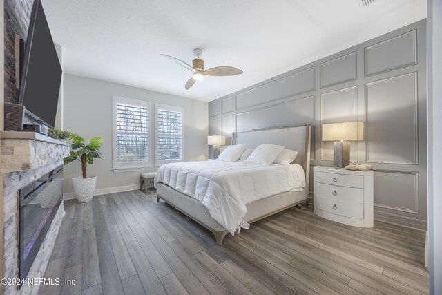 94 Hickory Pine Dr, Saint Augustine, FL 32092 - bedroom featuring a decorative wall, a fireplace, wood finished floors, a ceiling fan, and baseboards