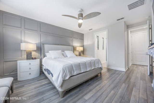 bedroom with ceiling fan, light hardwood / wood-style floors, and ensuite bathroom