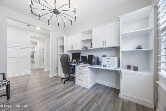 office space featuring built in features, a chandelier, washer / dryer, built in desk, and light wood-type flooring