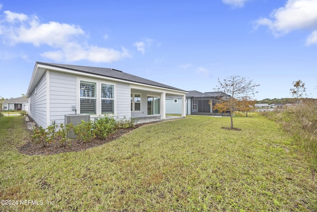 rear view of house with central air condition unit and a yard