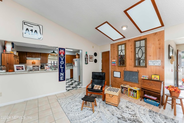 sitting room with a textured ceiling, wooden walls, light tile patterned floors, and vaulted ceiling