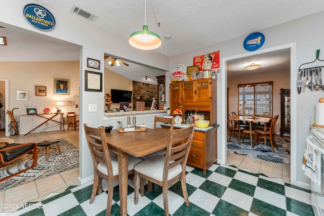 tiled dining room with ceiling fan, a textured ceiling, and vaulted ceiling