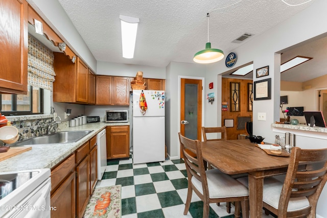 kitchen with decorative light fixtures, sink, white appliances, and a textured ceiling