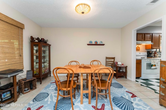 dining space with a textured ceiling and light tile patterned flooring