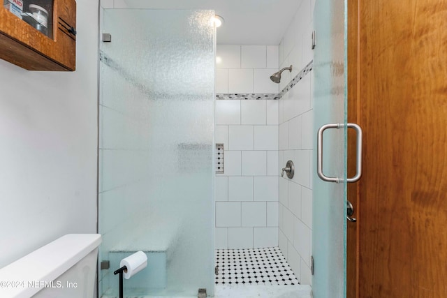 bathroom with toilet and a shower with door