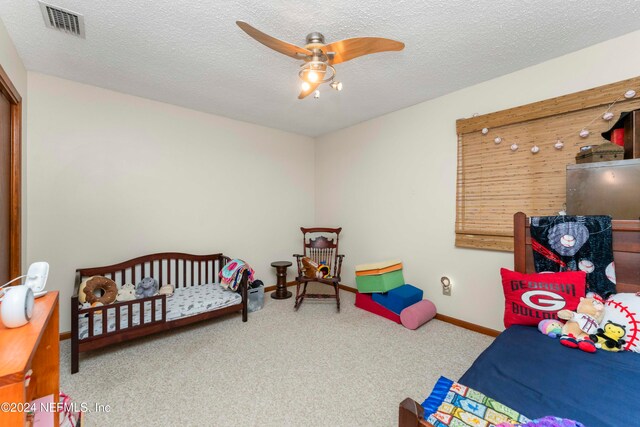 bedroom with ceiling fan, carpet floors, and a textured ceiling