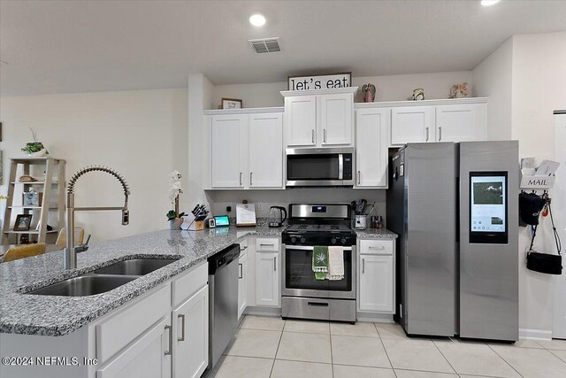 kitchen with kitchen peninsula, sink, white cabinets, and appliances with stainless steel finishes