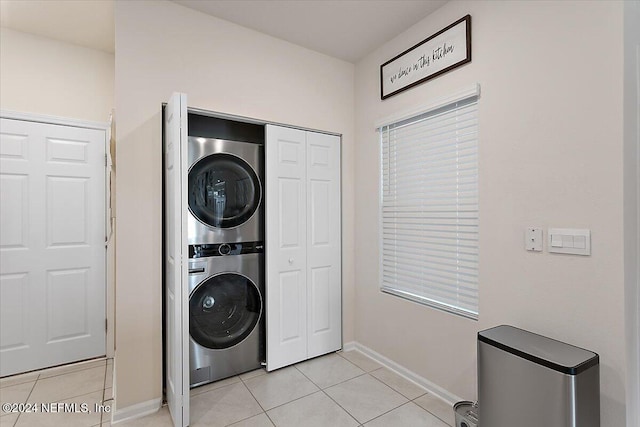 clothes washing area featuring light tile patterned flooring and stacked washer / dryer