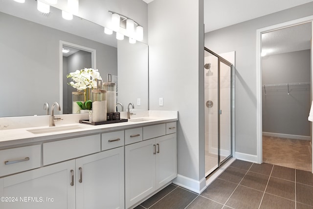 bathroom with a shower with door, vanity, and tile patterned flooring