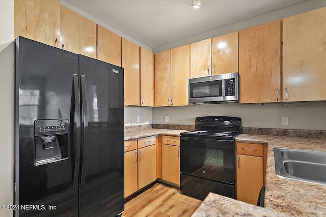 kitchen featuring black appliances, sink, and light hardwood / wood-style flooring